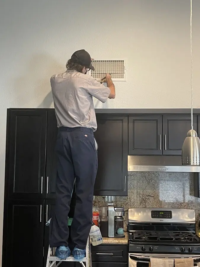 Technician inspecting an air vent during HVAC service in Greenbelt
